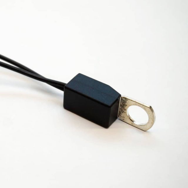 Close-up of Product 900-0059, a small black block with attached wires and a silver metal ring terminal, on a plain white background.