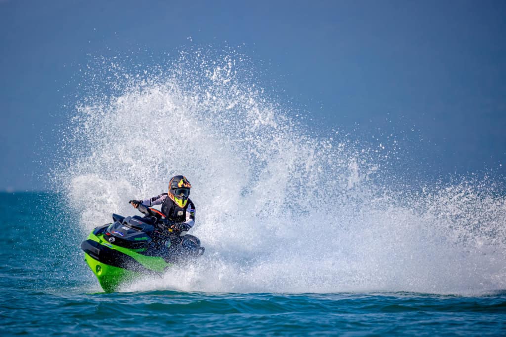 Person riding a jet ski on the ocean, creating a large splash of water.