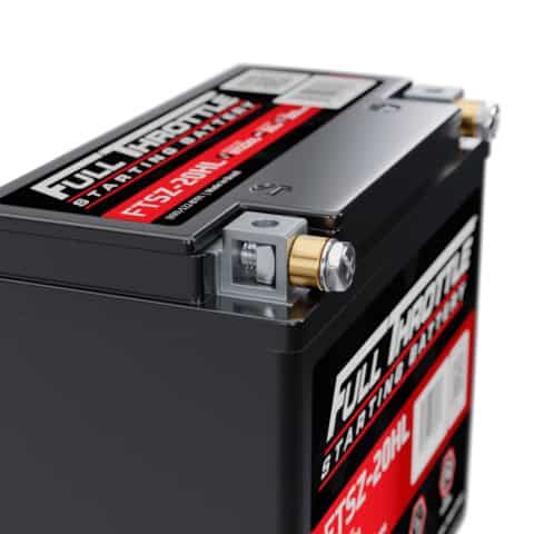 Close-up of a Full Throttle starting battery with red and black labels, showing metal terminals and part of the battery's rectangular body.