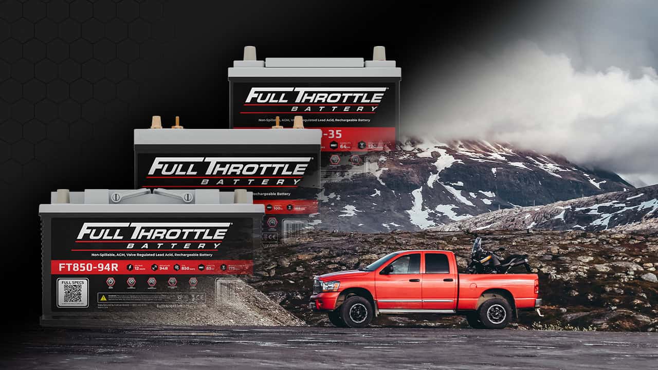 Three Full Throttle batteries of varying sizes are next to a red pickup truck on a rocky landscape with snowy mountains in the background.