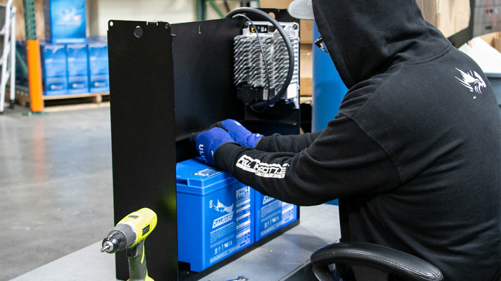 A man in a hoodie is building a Fullriver Battery PowerVault.