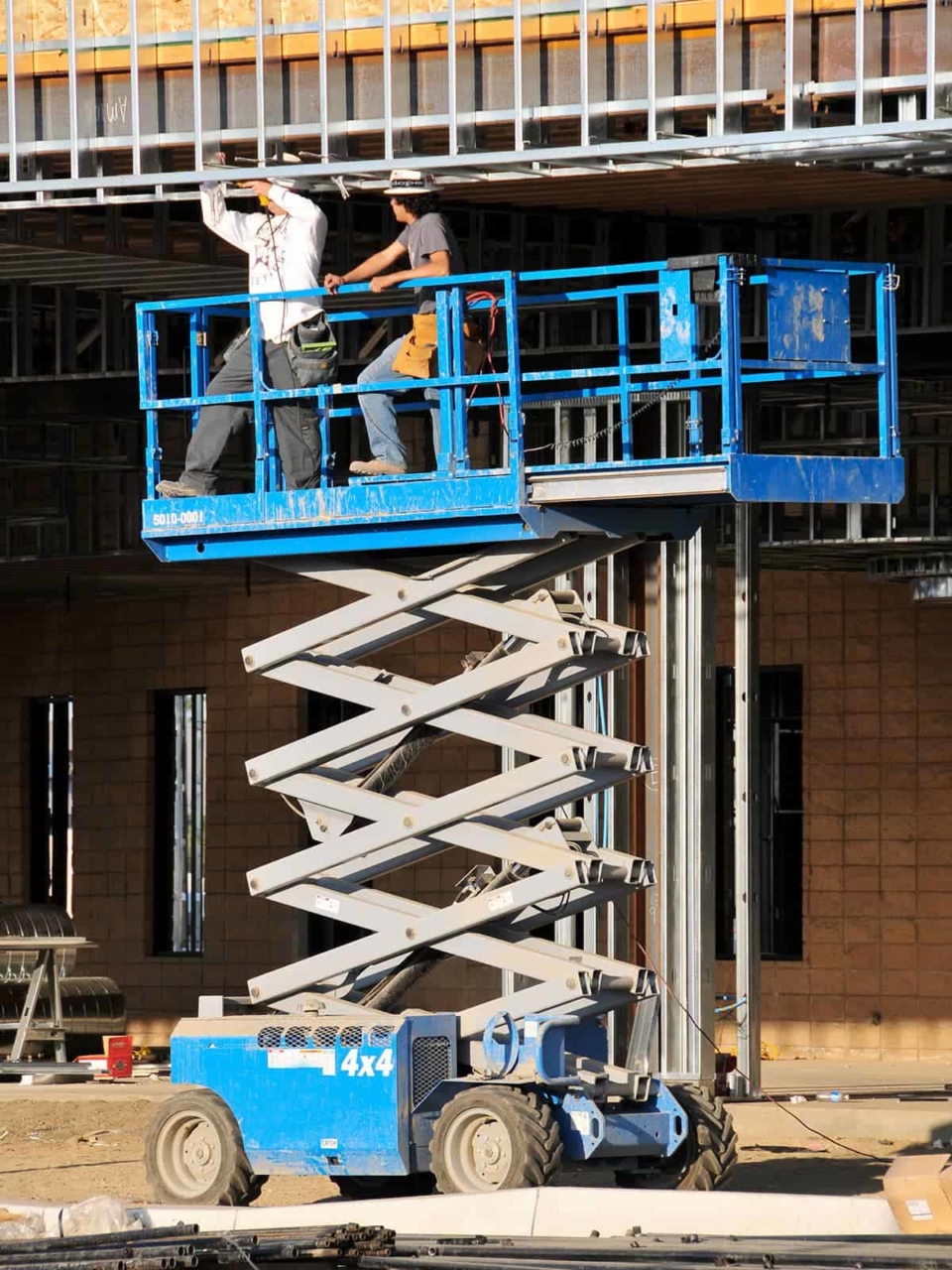 Workers standing on an aerial work platform working on a building