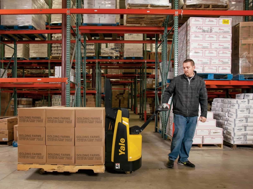 Man using an electric pallet jack in warehouse