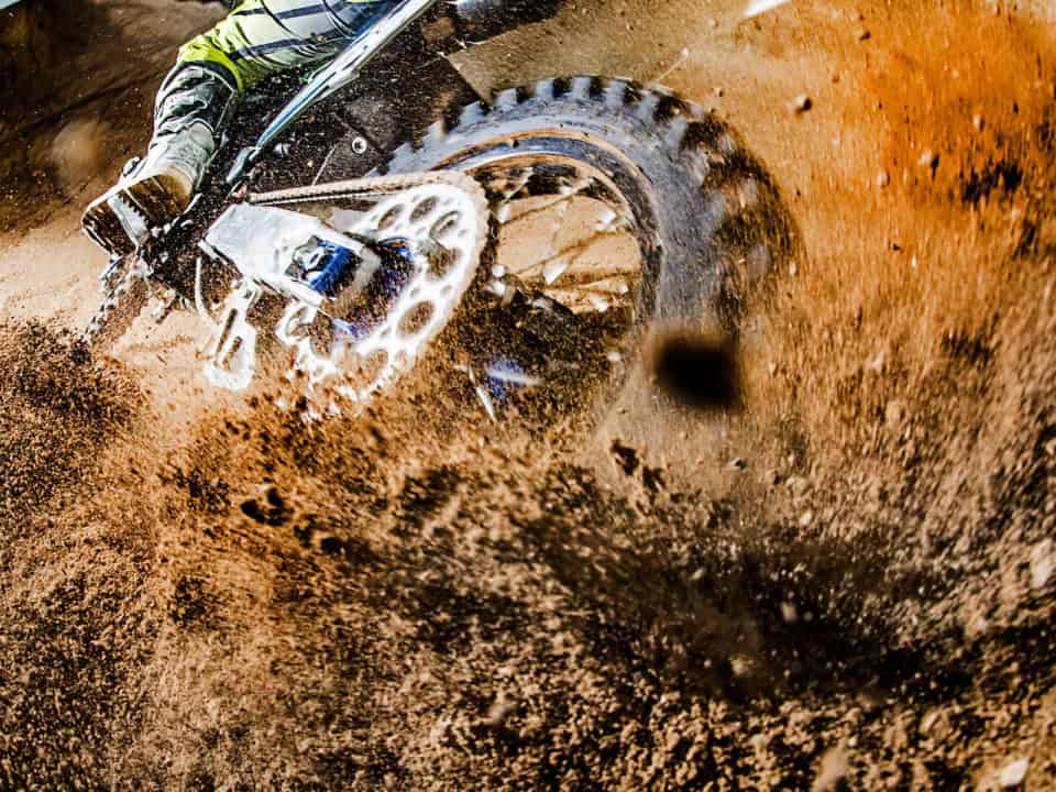 Close-up of a dirt bike tire kicking up mud during a ride.