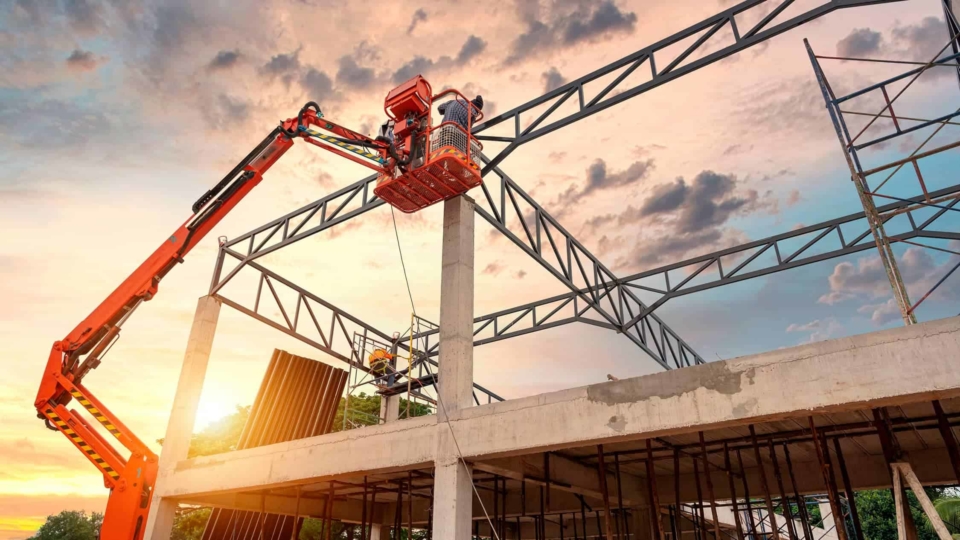 Workers in an aerial work platform bucket working on metal structure of a commercial building