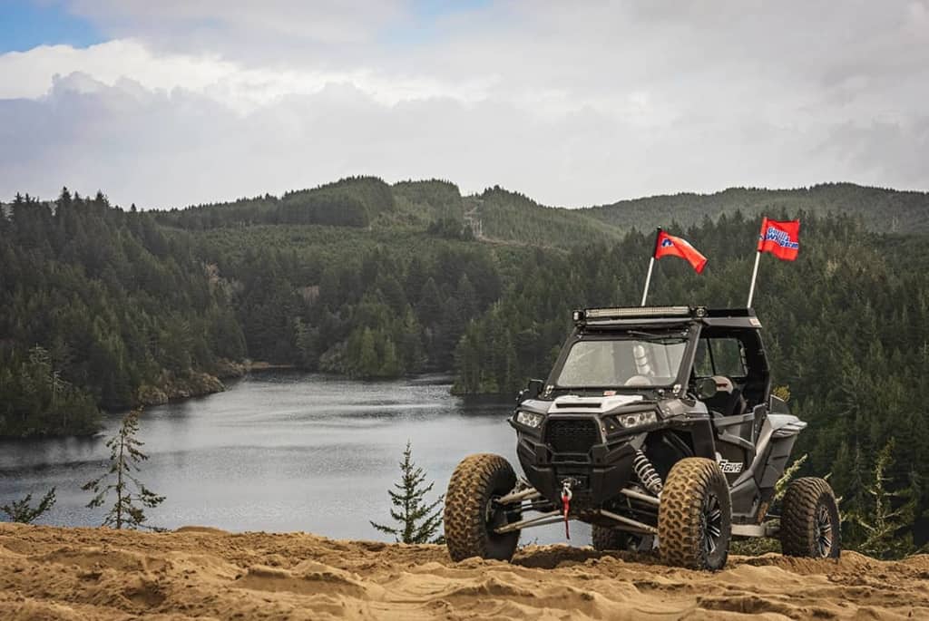 A UTV sits in front of a scenic lake surrounded by lush green trees in Winchester, Oregon.