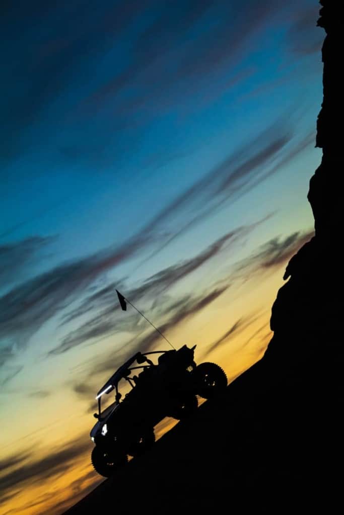 A silhouette of a UTV during blue hour near a cliff face.